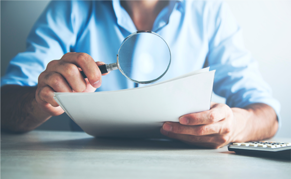 בדיקה ידנית מדוקדקת יכולה לעלות על חלק מהתמונות הערוכות, אולם בקצב נמוך ובמחיר גבוה. אדם סוקר מאמר עם זכוכית מגדלת | Shutterstock, Tiko Aramyan