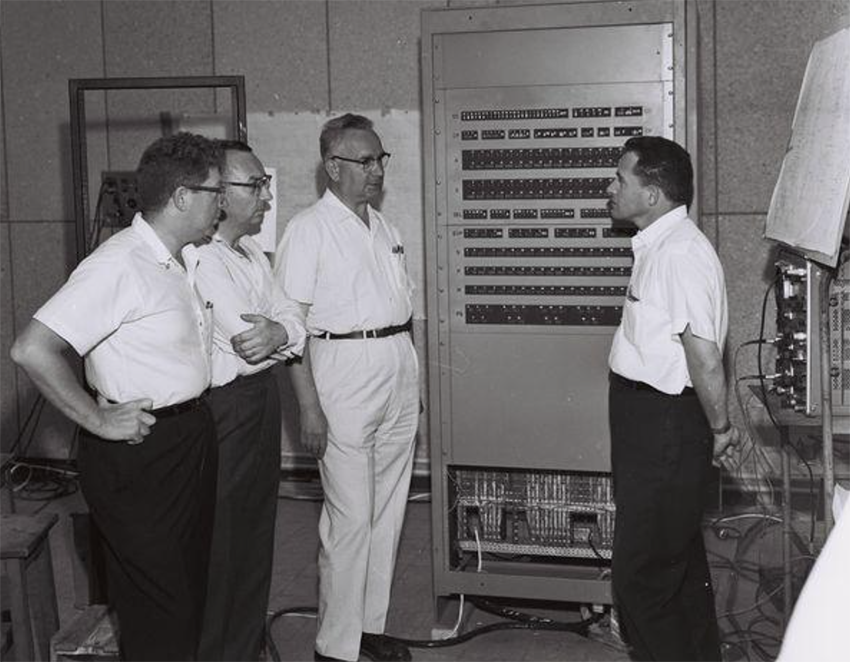 ב-1960 הפגיש אסתרין את רוכמן עם חיים לייב פקריס, ראש המחלקה למתמטיקה שימושית במכון ויצמן, שיזם את הקמת ויצק. מימין לשמאל: שמיל רוכמן, חיים לייב פקריס, צבי ריזל, ג'רלד אסתרין | ארכיון מכון ויצמן