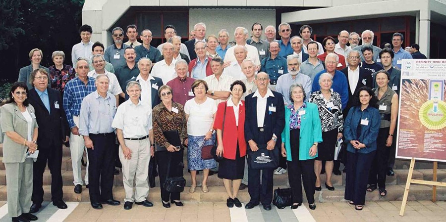 לא פרש באמת, וממשיך בעשייה המדעית. וילצ'ק (רביעי מימין בשורה התחתונה) בכינוס במכון ויצמן לכבוד יום הולדתו ה-65, בשנת 2000 (לידו רות ארנון) | צילום: מכון ויצמן למדע