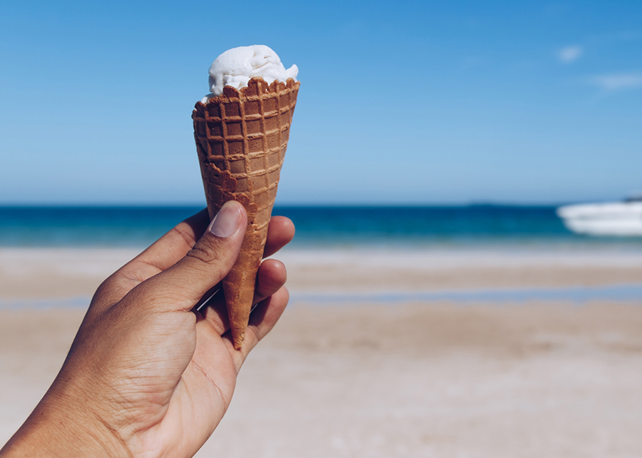 כשהטמפרטורה עלתה נצפתה עלייה גם בצריכת הסוכר. יד אוחזת גביע גלידה בחוף הים | SOUTHERNTraveler, Shutterstock