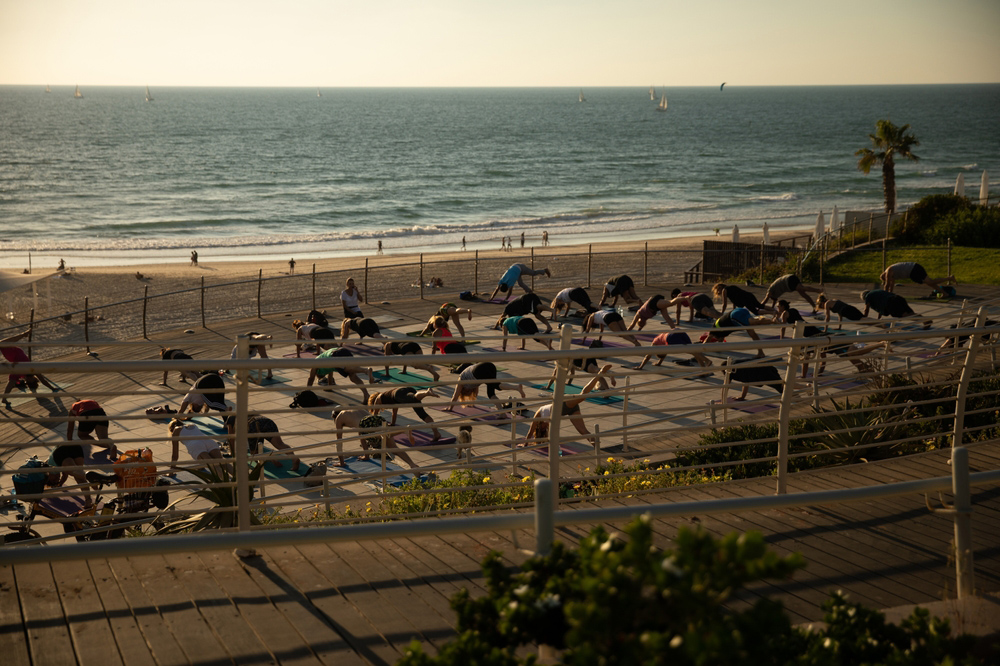מחקר של המשרד להגנת הסביבה והמכון לחקר ימים ואגמים מצא שהים התיכון מתחמם מהר יותר מהקצב העולמי הממוצע. אנשים מתאמנים ביוגה על שפת הים התיכון | MOSTO photography, Shutterstock