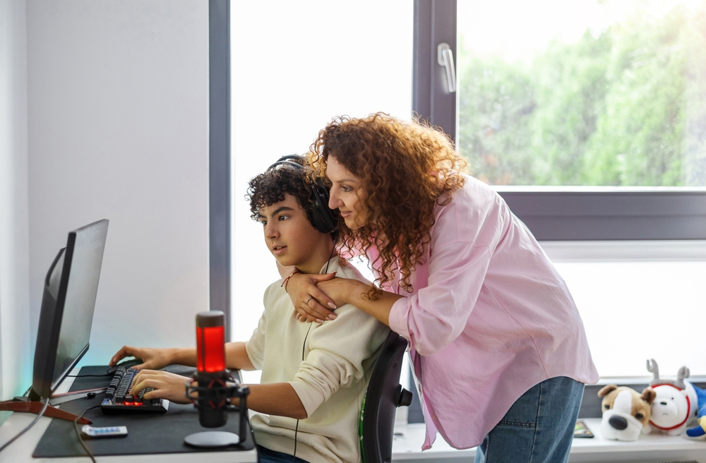 תפקיד ההורים בימינו אינו להילחם בכל פלטפורמה חדשה, אלא להיות נוכחים. אם ובן מול משחק מחשב | pikselstock, Shutterstock