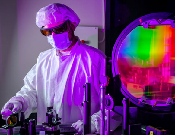 חוקר עומד לצד מערכת הלייזר ששימשה בניסוי