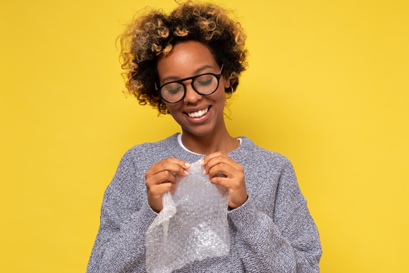 אישה מחייכת כשהיא מפוצצת בועיות בעטיפת פצפצים | Shutterstock, Koldunova Anna