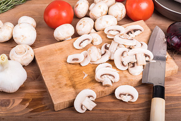 פטריות, שום ובצל על קרש החיתוך | Ostranitsa Stanislav, Shutterstock