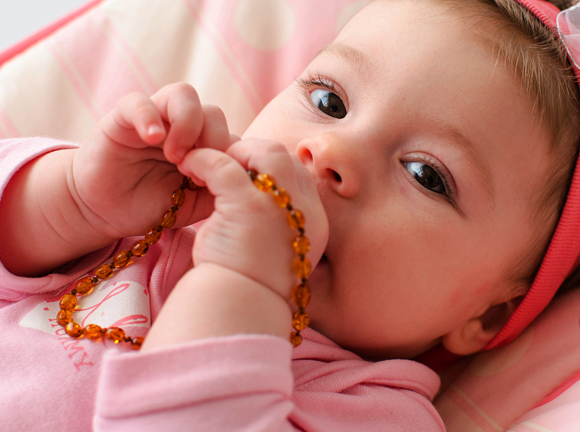 צעצוע שאינו מועיל, אבל עלול להיות מסוכן ולגרום לחניקה, לחנק ולזיהומים. תינוק עם שרשרת ענבר | צילום: Shutterstock