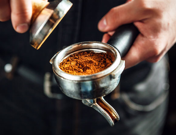 בריסטה מכניס גרגרי קפה למכונת אספרסו | Shutterstock, luckyraccoon