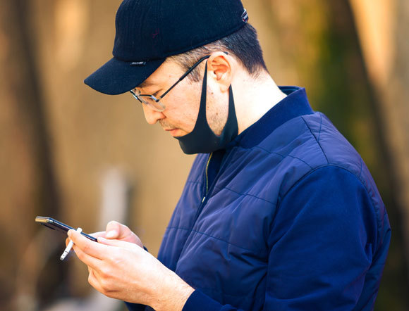 אדם מעשן בזמן שפניו מכוסות במסכה | V.Baturin, Shutterstock